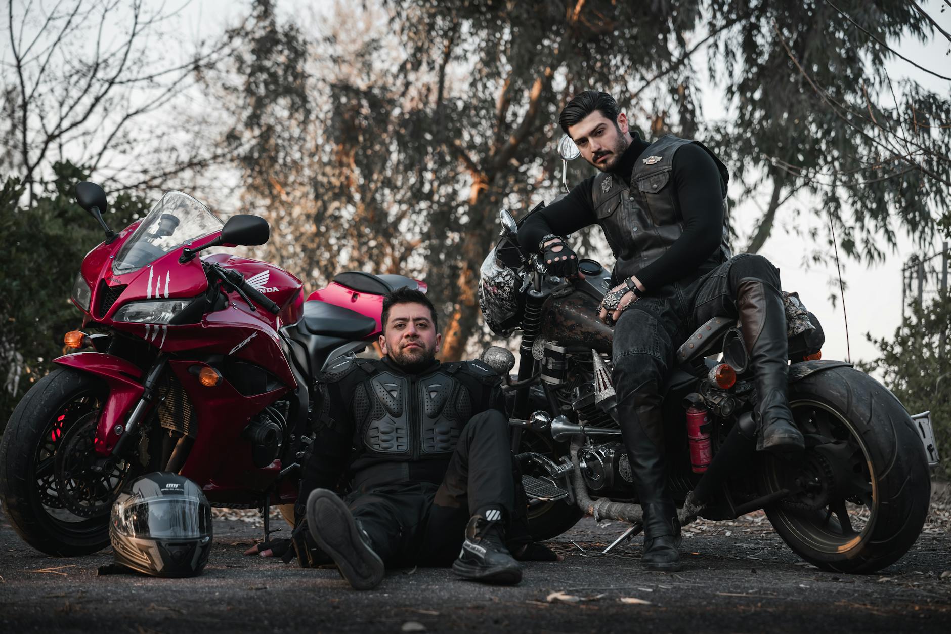 Dwaj motocykliści w skórzanych kurtkach pozują przy motorach na zewnątrz